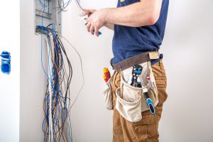 Electrician Builder at work, examines the cable connection in the electrical line.